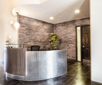 a curved reception desk in a hotel lobby with a brick wall at The Timbers Apartments, Evansville, Indiana